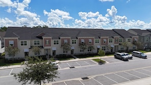 A row of townhouses with a parking lot in front. - Family 5BR at Solara with Private Pool (Kissimmee)