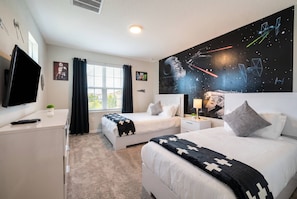 Een hotelkamer met twee bedden, een televisie, een raam met gordijnen en een muurschildering met het thema Star Wars.