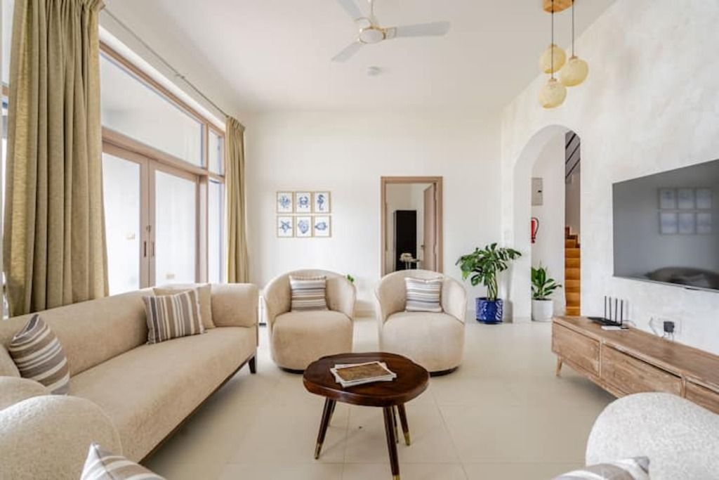 A living room with a sofa, armchairs, a coffee table, a TV, and a ceiling fan.