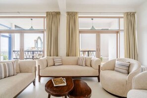 A modern living room with a sofa set, a coffee table, and large windows with curtains.
