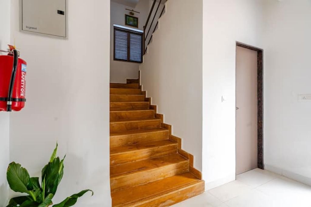 Eine Treppe führt zu einer oberen Etage, ein Feuerlöscher ist an der Wand angebracht und eine Tür befindet sich auf der rechten Seite.