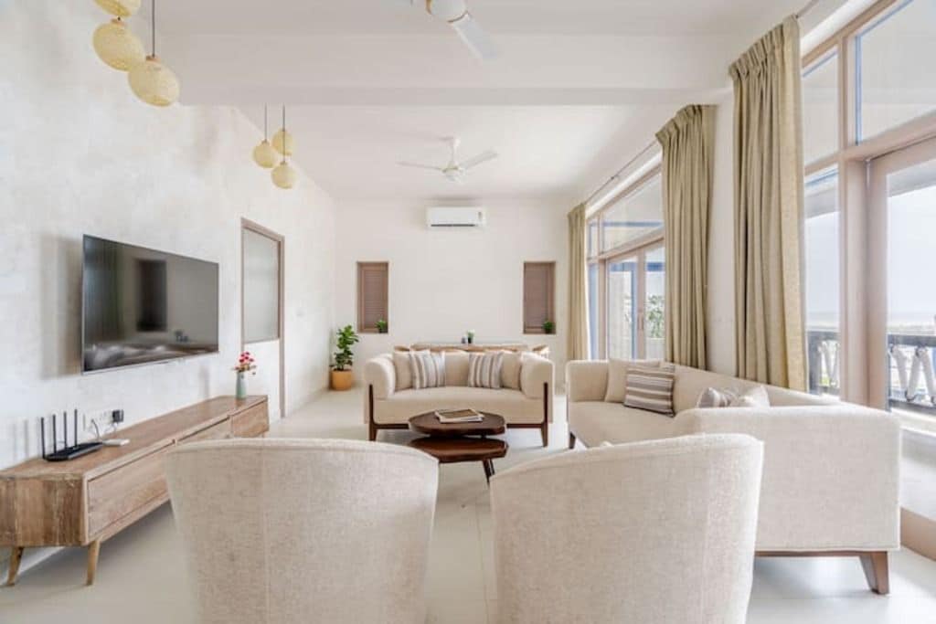 Ein modernes Wohnzimmer mit Flachbildfernseher, Sofas, einem Couchtisch und einem Deckenventilator.
