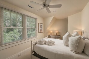 Ein Schlafzimmer mit einem Bett, zwei Nachttischen, einem Deckenventilator und einem Fenster mit Jalousien.