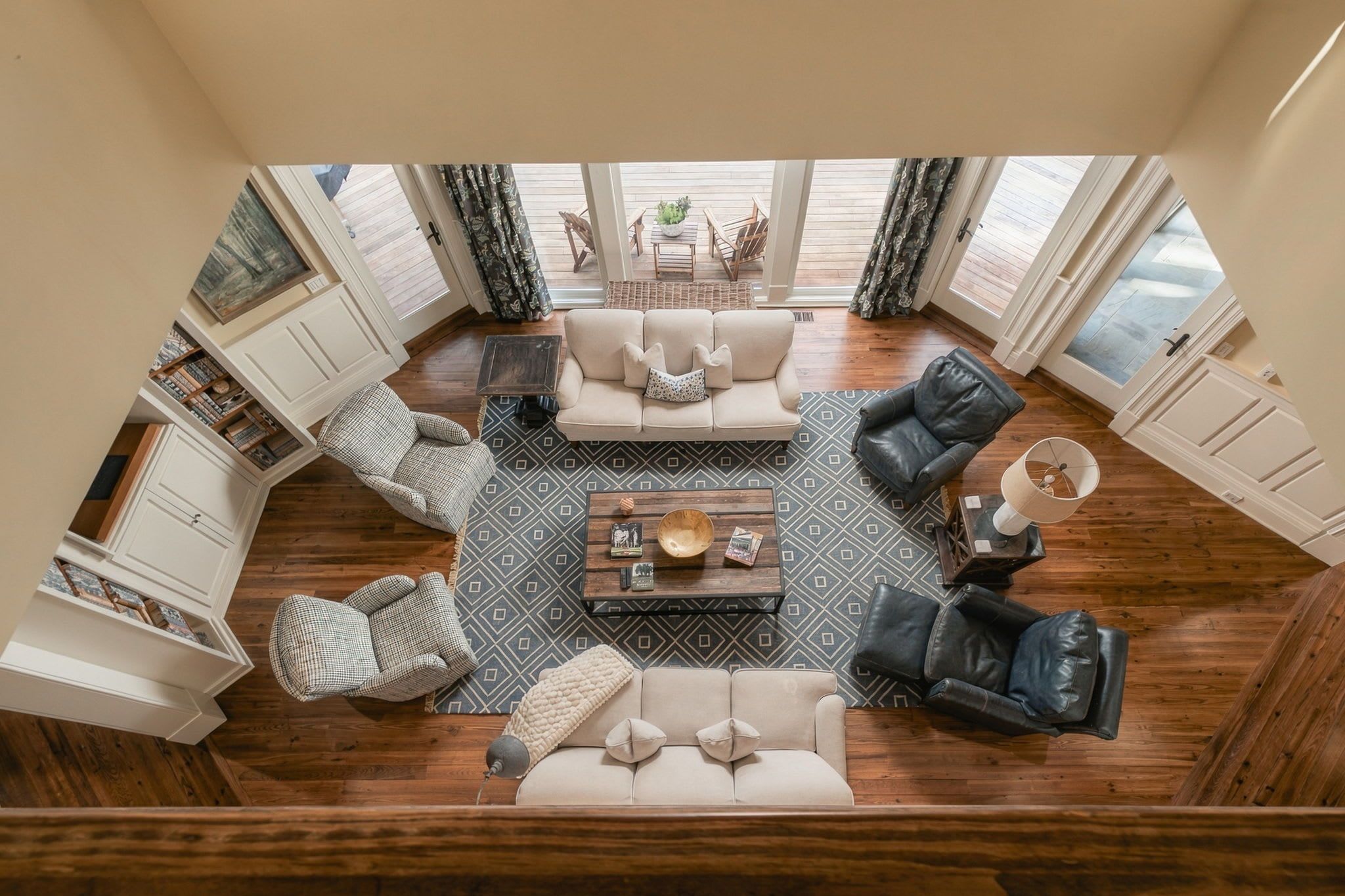 Ein geräumiges Wohnzimmer mit einem Couchtisch in der Mitte, umgeben von Sofas und Sesseln, mit Blick auf einen Balkon und Gartenmöbel.