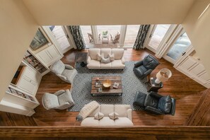Amplia sala de estar con una mesa de centro, rodeada de sofás y sillones, y vistas a un balcón con mobiliario exterior.