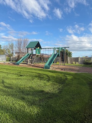 A playground with two slides and a climbing structure.