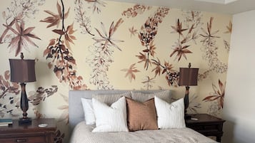 Een slaapkamer met een bed, twee nachtkastjes, een plafondventilator en bloemenbehang.
