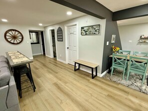 A hallway with a wooden floor, a bench, a dining area with a table and chairs, and a door labeled 'PRIVATE.'