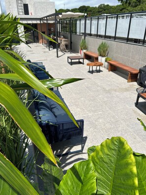 Eine Dachterrasse mit Sitzgelegenheiten im Freien, einer Pergola und Kübelpflanzen.