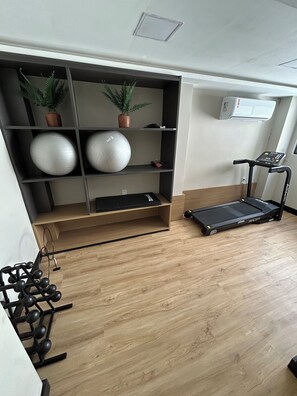 Ein Fitnessraum mit Laufband, Gymbällen und einer Wand-Klimaanlage.