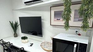 Kompakti keittiö, jossa on taulutelevisio, mikroaaltouuni ja jääkaappi.