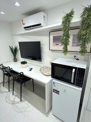 Eine kompakte Küche mit Flachbildfernseher, Mikrowelle und Kühlschrank.