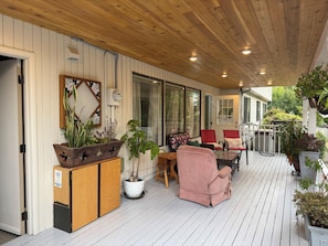 A covered porch with wooden flooring, potted plants, and outdoor furniture. - Clyde Hill retreat house (Clyde Hill)