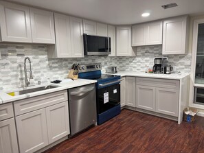 A modern kitchen with white cabinets, a stainless steel dishwasher, a blue oven, and a microwave. - Clyde Hill retreat house (Clyde Hill)