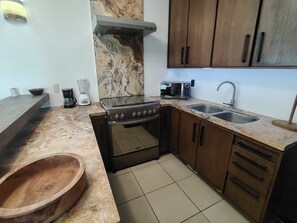 A compact kitchen with a stove, oven, microwave, and double sink. - Casa Posada del Sol (Manzanillo)