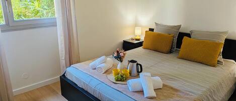 Habitación de hotel con cama, mesitas de noche, ventana con cortinas y vistas a zonas verdes.