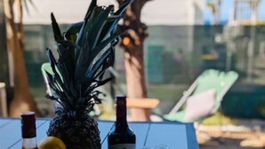 Una mesa con una piña, limones, uvas y dos botellas de vino, además de saleros y pimenteros con forma de estrella.