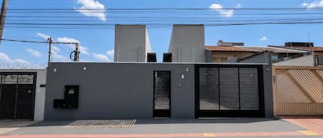Propiedad resguardada con portón metálico, una puerta pequeña y un camino de concreto con pavimentación táctil.