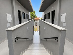 A modern building with a central staircase flanked by walls with windows and light fixtures. - Fully furnished apartment, 5 min walk from UFMS (Federal University of Mato Grosso do Sul), near the University Hospital (HU). (Campo Grande)