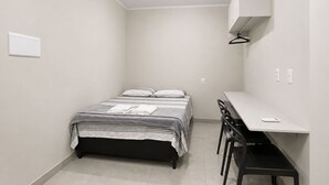 Habitació petita i senzilla amb llit, escriptori i cadira.