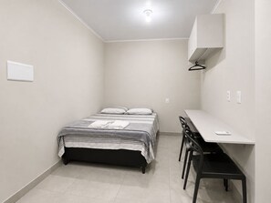 A small, clean room with a bed, a desk, and a chair. - Fully furnished apartment, 5 min walk from UFMS (Federal University of Mato Grosso do Sul), near the University Hospital (HU). (Campo Grande)