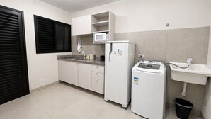 Cuina compacta amb armaris blancs, microones integrat, nevera, rentadora i un rentaplateres.