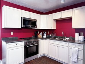 A kitchen with white cabinets, a microwave, a stove, and a sink. - Highlands Gateway | Games, Fire Pit, 4BR Fun (Louisville)