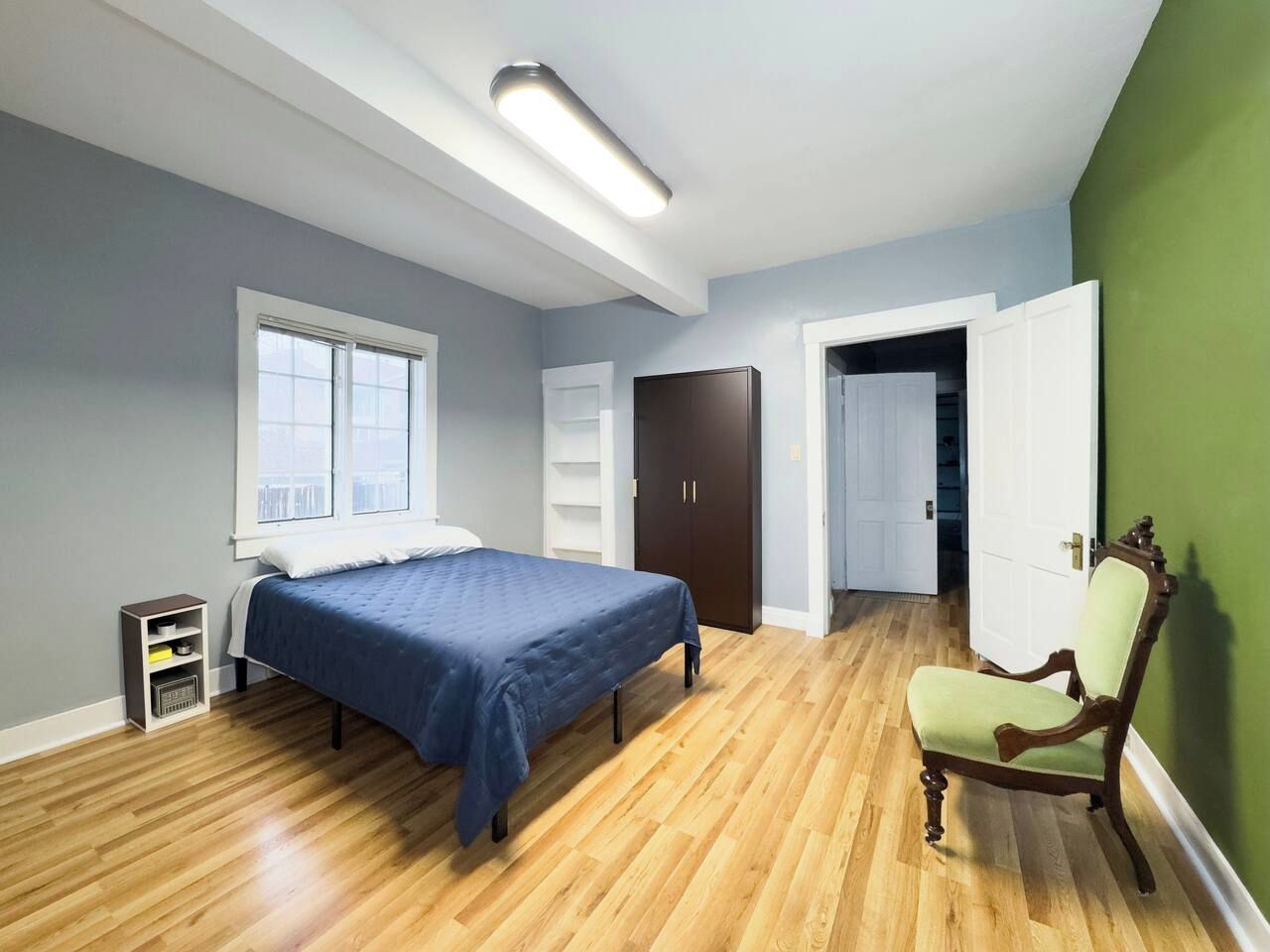 Une chambre à coucher comprenant un lit, une chaise, une armoire et une porte donnant sur une autre pièce.