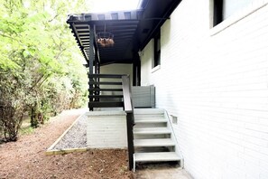 A staircase leading to a covered porch area with a hanging basket. - Suite 1275 (East Point)