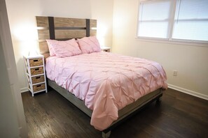 A bedroom with a bed, bedside tables, and a window. - Suite 1275 (East Point)