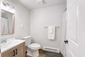 A bathroom with a white sink, toilet, and shower curtain.
