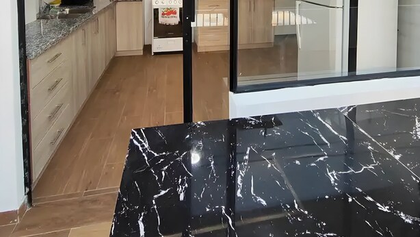 Une cuisine moderne avec des meubles blancs, une cuisinière et un réfrigérateur.