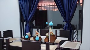Un coin repas avec une table dressée pour quatre personnes, entourée de chaises, et un grand miroir qui reflète la pièce.