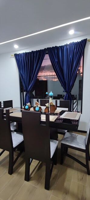 A dining area with a table set for four, surrounded by chairs, and a large mirror reflecting the room. - Modern Luxury Home! A peaceful retreat surrounded by nature! (Loja)