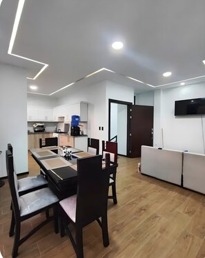 Una cocina moderna con armarios blancos, estufa integrada y dispensador de agua.