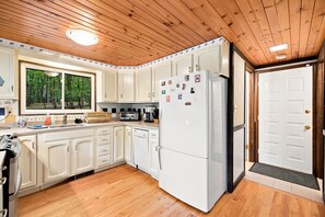 A kitchen with wooden cabinets, a refrigerator, and a window with a view of trees. - Pet-Friendly w/Deck & Games in The Woods Resort (Hedgesville)