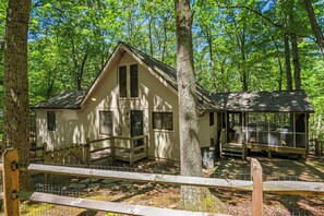 A cabin with a porch, surrounded by trees. - Pet-Friendly w/Deck & Games in The Woods Resort (Hedgesville)