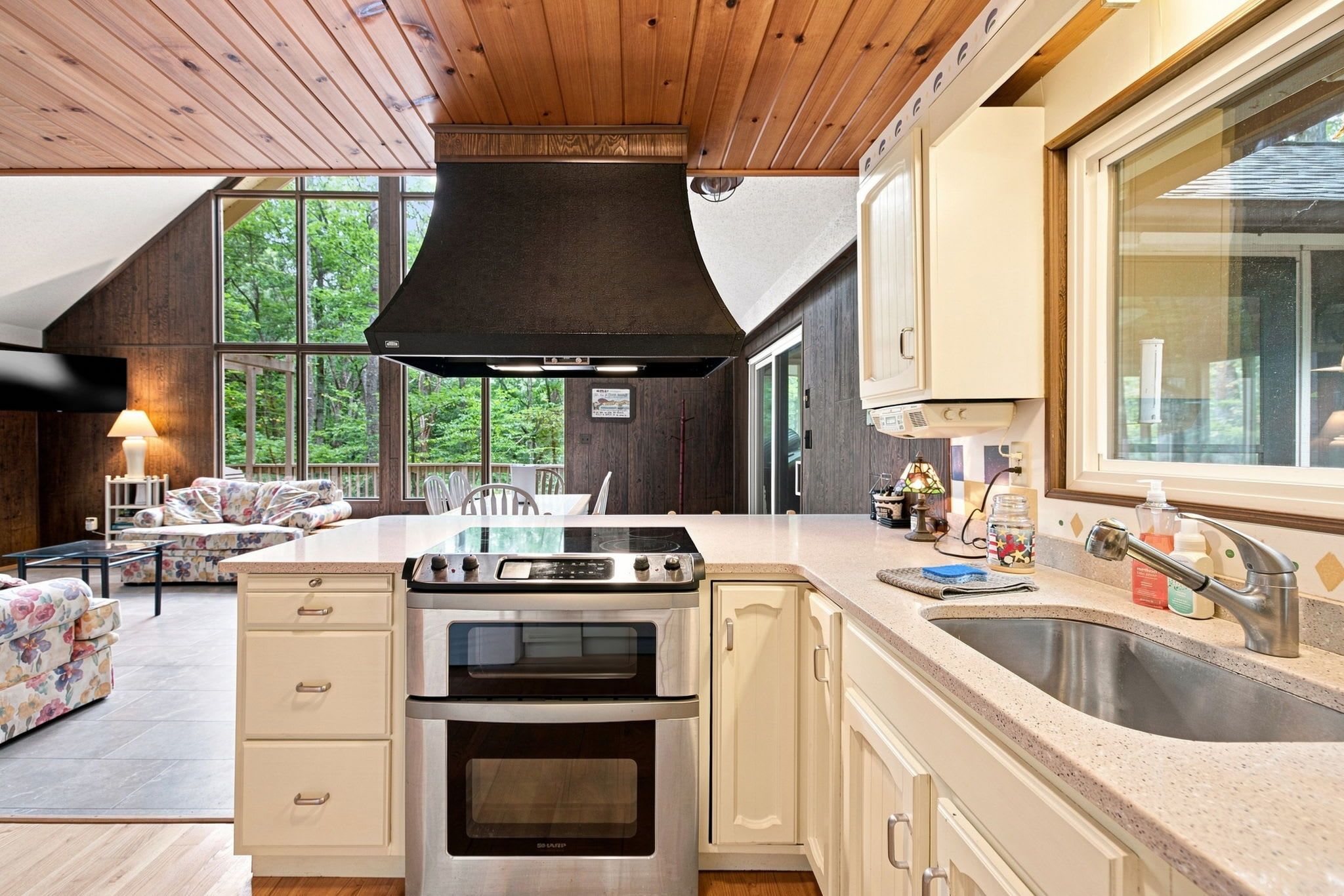 Una cocina moderna con una isla grande, electrodomésticos de acero inoxidable y vistas al exterior a través de amplios ventanales.