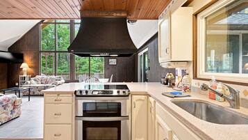 Una cocina moderna con una isla grande, electrodomésticos de acero inoxidable y vistas al exterior a través de amplios ventanales.
