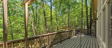 A wooden deck with a railing, surrounded by trees.