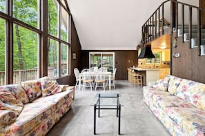 Amplia sala de estar con mesa y sillas, un sofá y una zona de cocina con barra.