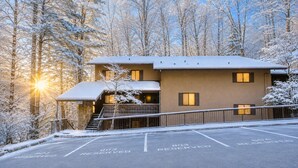 A two-story building with a snow-covered roof and a parking area marked with 'RESERVED' signs. - Smoky Laurel Cottage - Mountain Views & Fireplace! (Gatlinburg)