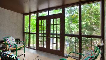 A room with large windows, a chair with a striped cushion, and a table.
