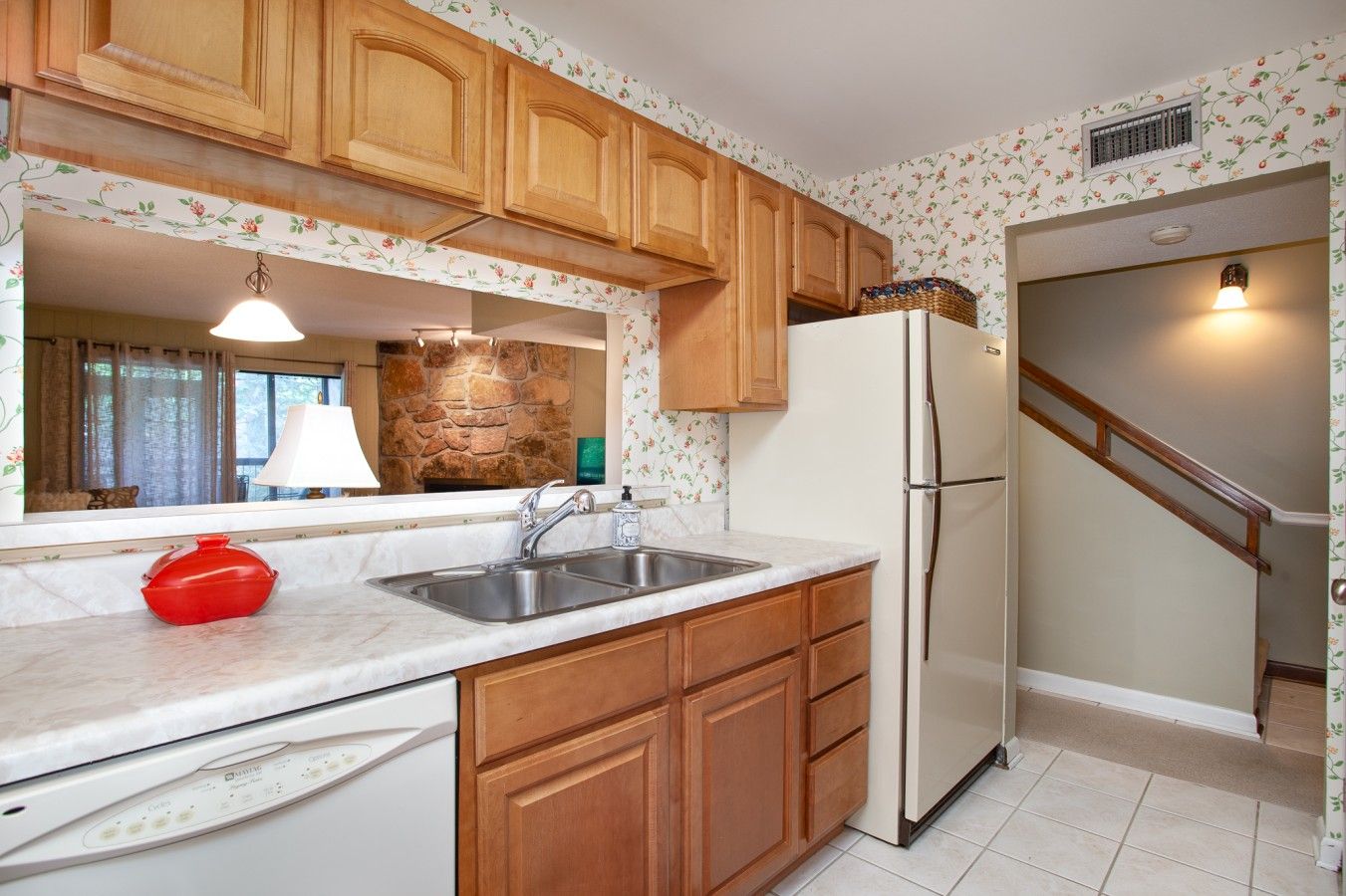 A kitchen with wooden cabinets, a white refrigerator, a sink, and a red pot on the counter.