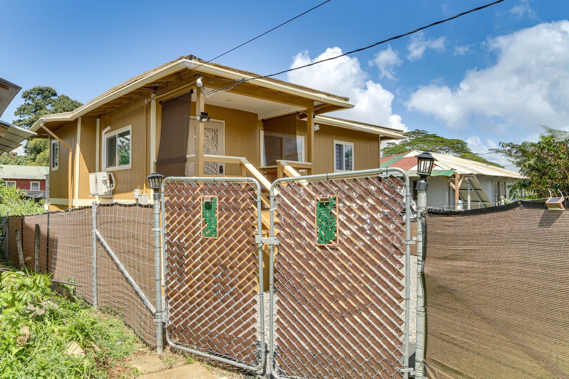 A two-story house with a fenced yard, a covered porch, and a satellite dish.