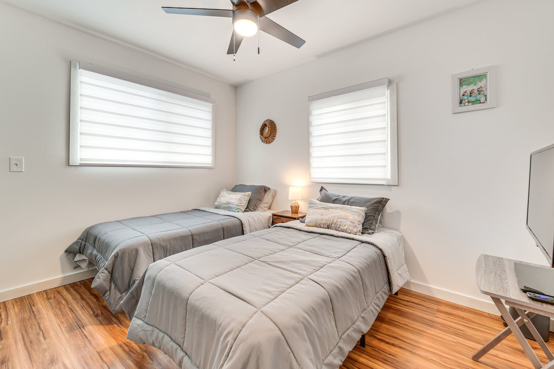 A bedroom with two beds, a ceiling fan, and a desk with a chair.