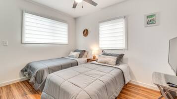 A bedroom with two beds, a ceiling fan, and a desk with a chair.