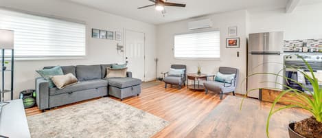 Una sala moderna con un sofá modular, una mesita redonda y un ventilador de techo.