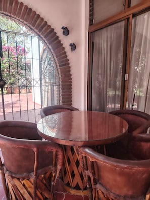 A round table with six chairs, a glass top, and a brick archway. - Silvia's House (Manzanillo)