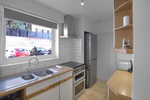 Una cocina moderna con un lavamanos doble, electrodomésticos de acero inoxidable y un ventanal con vistas a un estacionamiento.